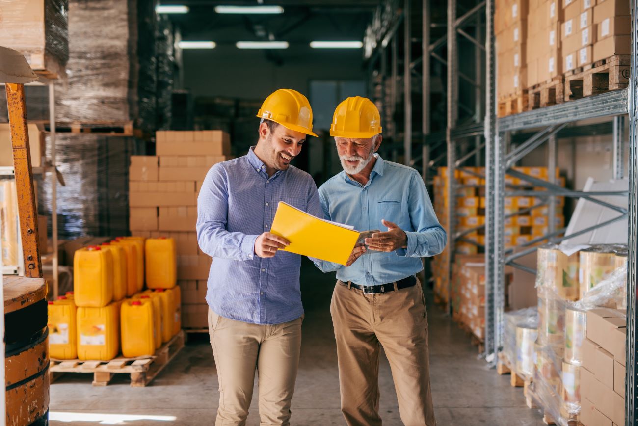 Workers in a warehouse looking through a spreadsheet