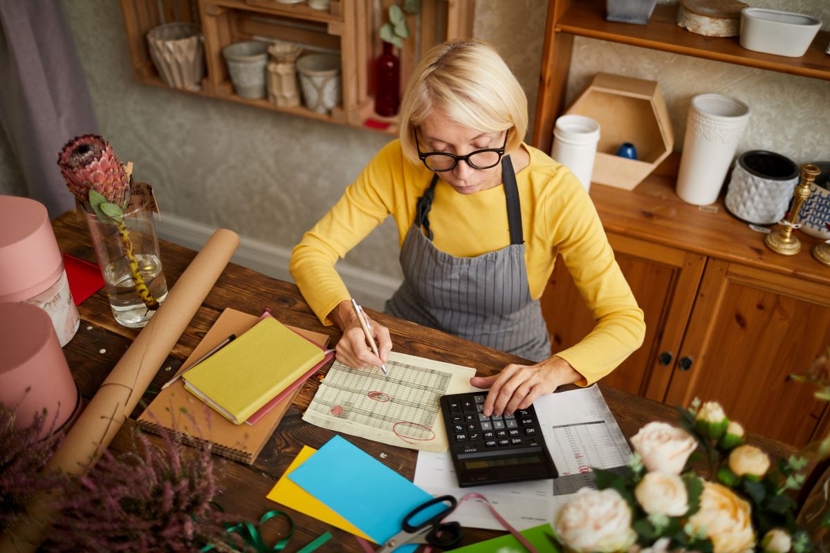 High angle portrait of female businesswoman counting finances using calculator in small shop